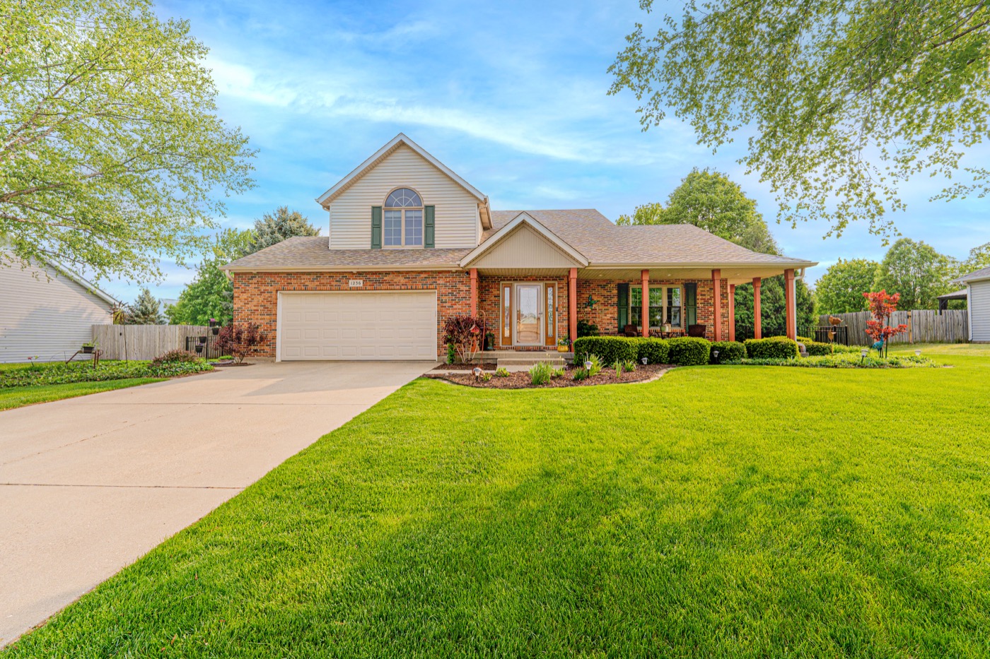 A two-storey brick home with a covered porch on a wide lawn